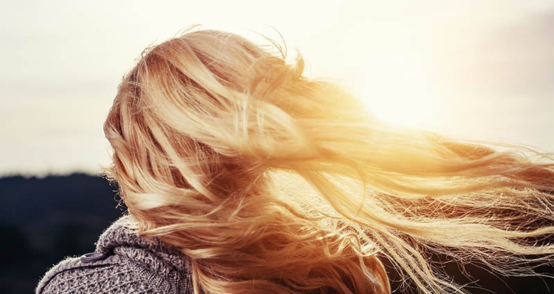 Mujer rubia usando champú desamarillador en cabello con luces